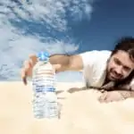 man in desert reaches for water